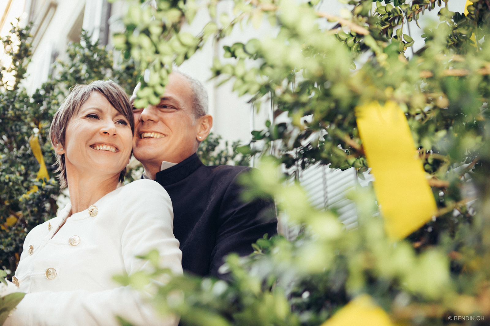 Brautpaar sich umarmend und lachend inmitten von Blumen